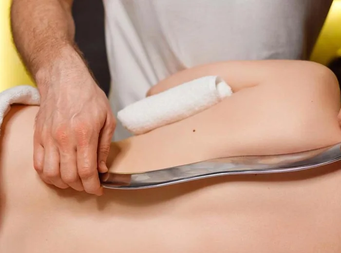 Instrument-assisted soft tissue work across a patient's lower back