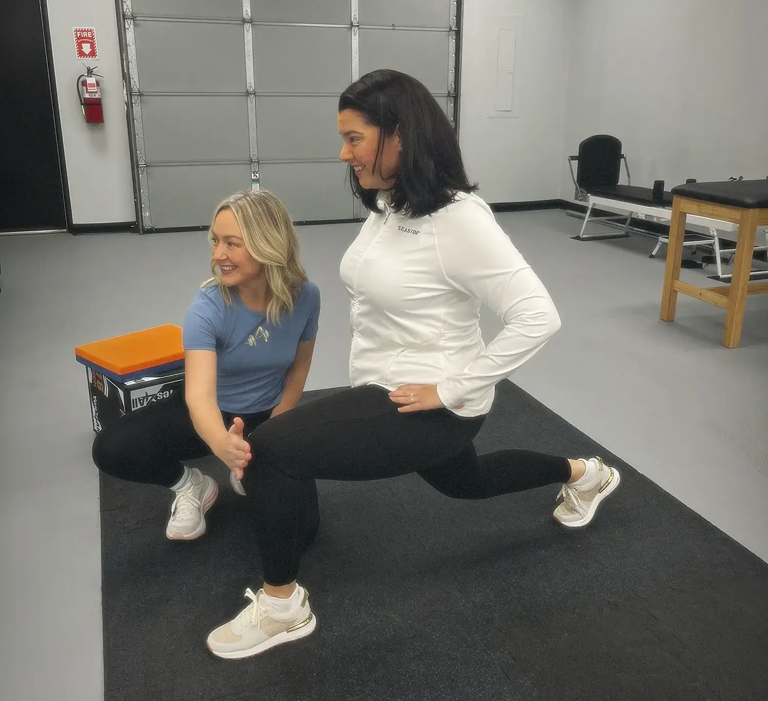 Physical therapist coaching a patient through a lunge in the clinic gym