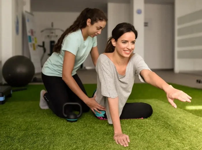 Therapist guiding a patient through a floor reach and rotation