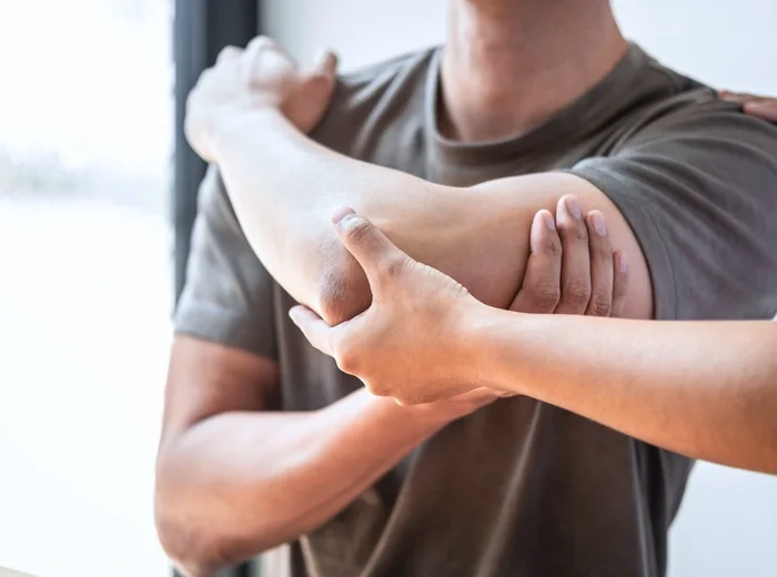 Clinician palpating a patient's elbow and forearm