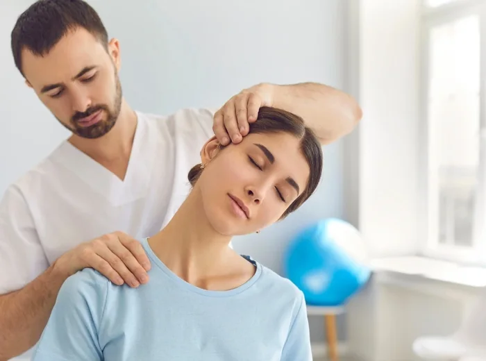 Therapist easing a seated patient's neck into a lateral stretch