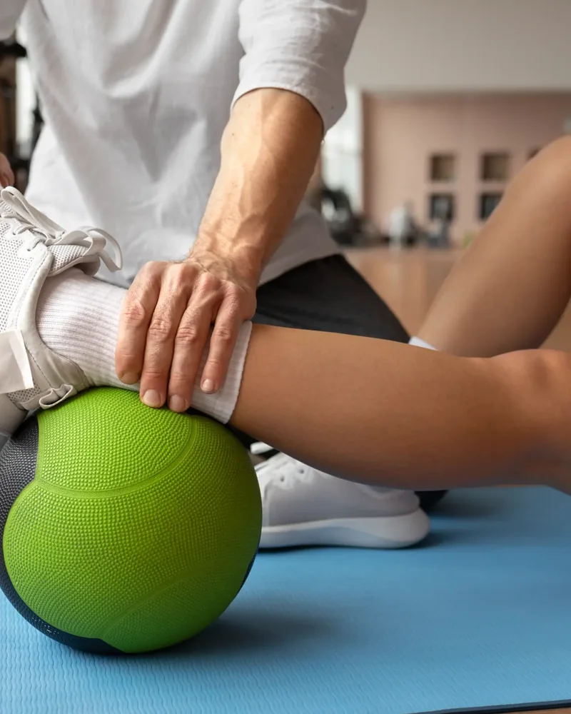 Therapist guiding a patient's knee through controlled range on an exercise ball