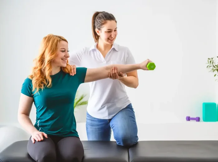 Therapist supporting a patient's arm through an overhead dumbbell press