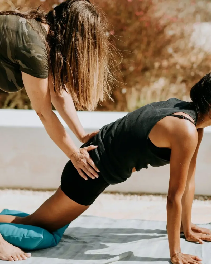 Coach cueing a woman through a plank outdoors