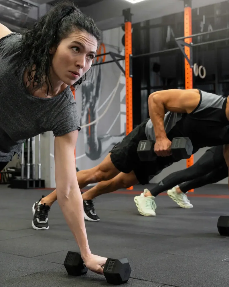 Group working through strength training with hex dumbbells in a gym