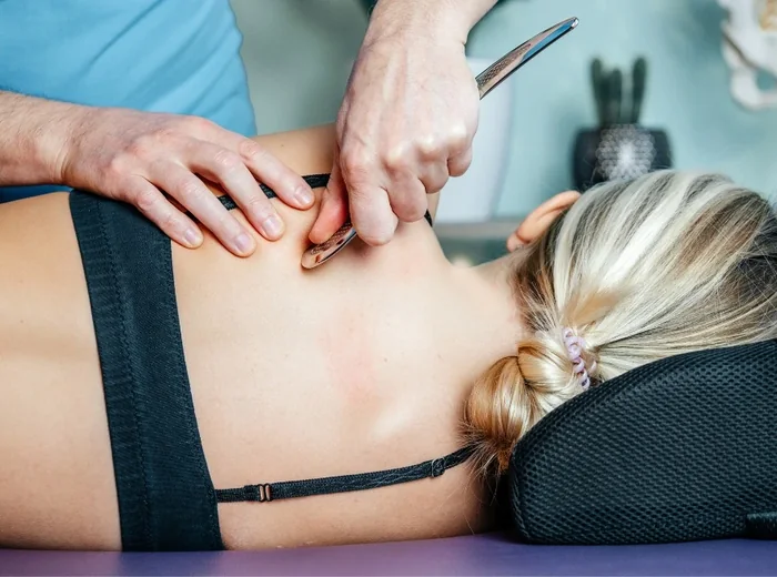 Practitioner working an instrument along a patient’s lower back