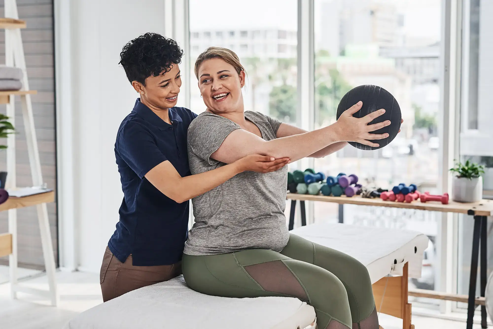 Physical therapist guiding a patient through a seated rotation exercise with a medicine ball