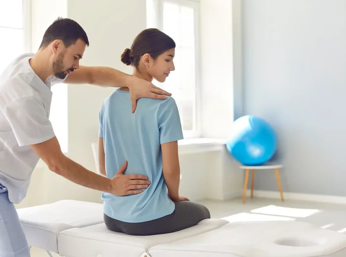 Therapist assessing a seated patient's spine and posture