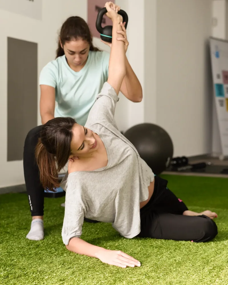 Therapist guiding an athlete through an assisted stretch on turf